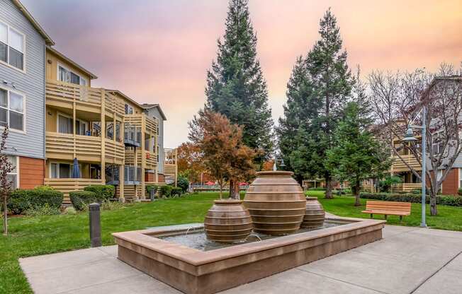 A courtyard with a fountain and apartment buildings in the background.
