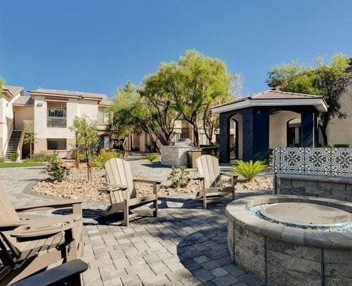 A patio with a hot tub and chairs is surrounded by a stone wall.