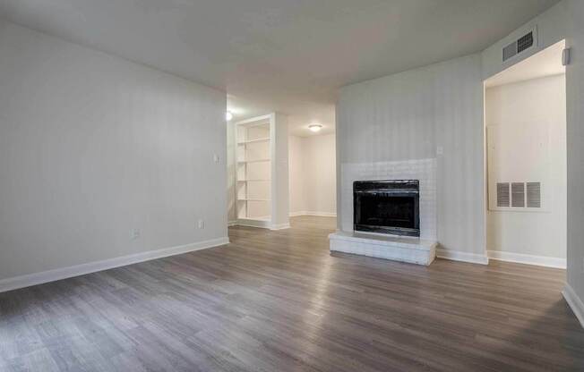 A spacious living room with a fireplace and hardwood floors.at 2400 Briarwest Apartments, Texas, 77077