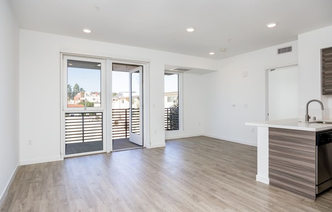 a living room and kitchen with sliding glass doors to a balcony