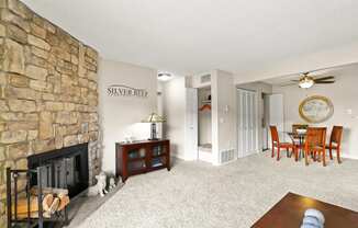 A living room with a stone fireplace and a dining table with chairs.
