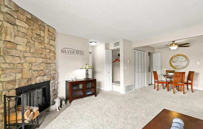 A living room with a stone fireplace and a dining table with chairs.