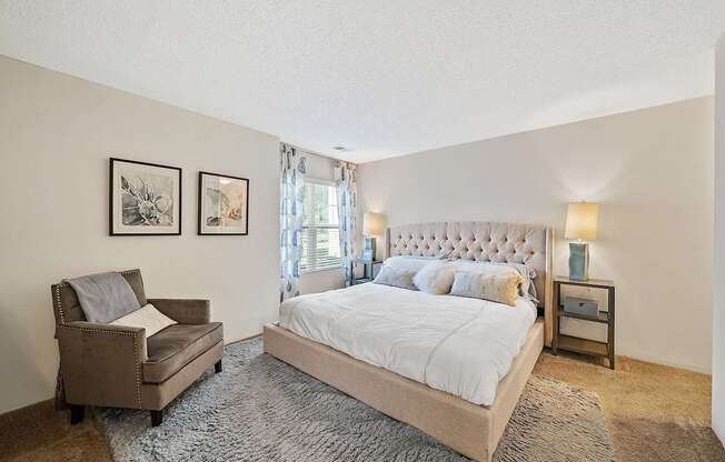 A bedroom with a large bed and a chair.