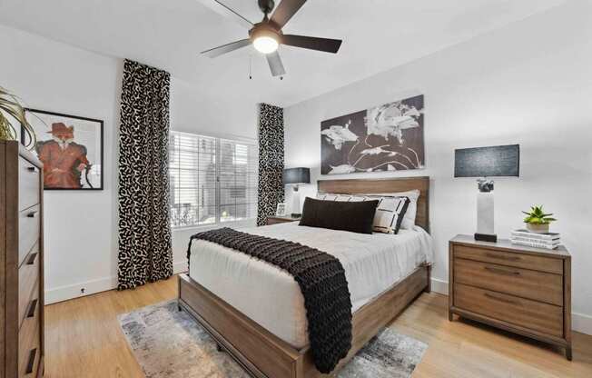 A bedroom with a large bed, a ceiling fan, and a painting of a cowboy on the wall.