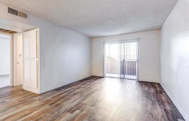 A room with wooden flooring and a window with blinds.