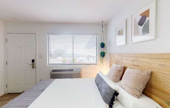 A bedroom with a bed, pillows, and a window with blinds.