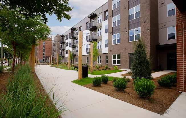 A long concrete walkway leads to a brick building with balconies.