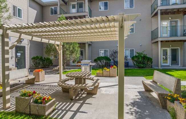 a patio with a picnic table and a pergola in front of a building
