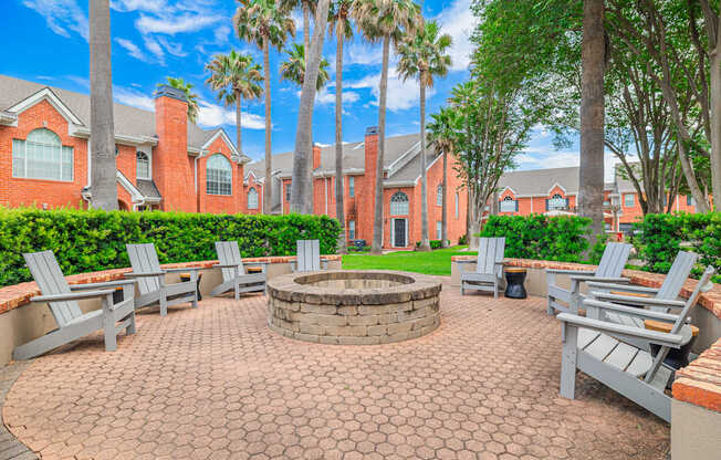 A brick patio with a fire pit and chairs.