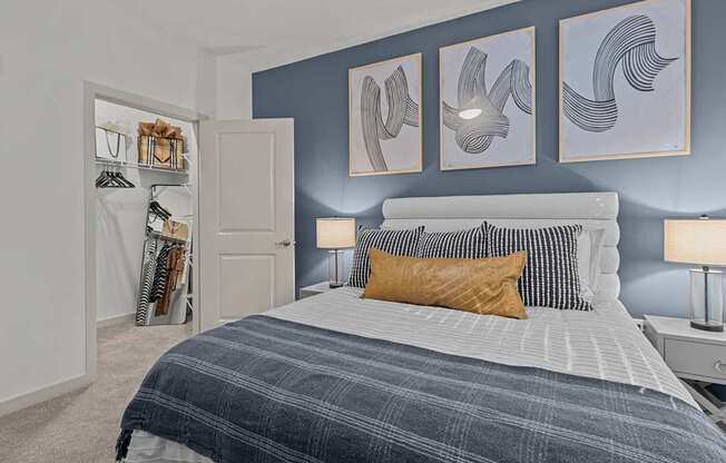 A bedroom with a bed, nightstand, and a closet with clothes hanging.