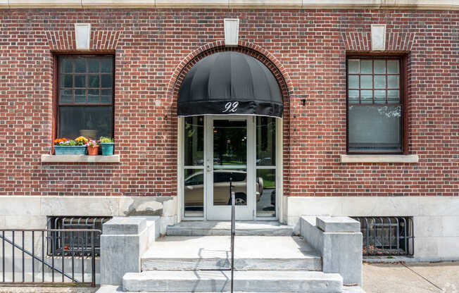 A brick building with a black awning and a glass door.