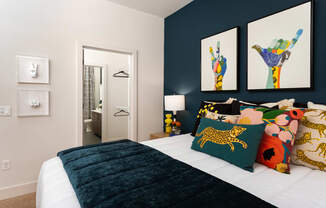 a bedroom with a bed with colorful pillows and pictures on the wall