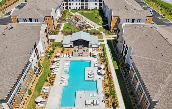 An aerial view of a large building complex with a swimming pool in the center.