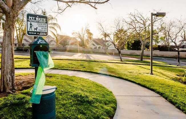 A sign on a post in a park instructs people to clean up after their pets.