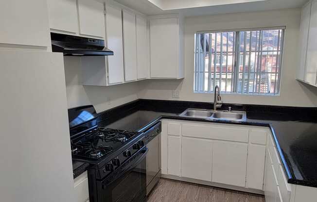 Kitchen with spacious white cabinets, gas range, and dishwasher at Northwood Apartments in Upland, California.