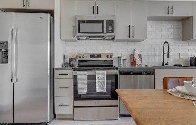 A modern kitchen with a refrigerator, oven, and microwave.