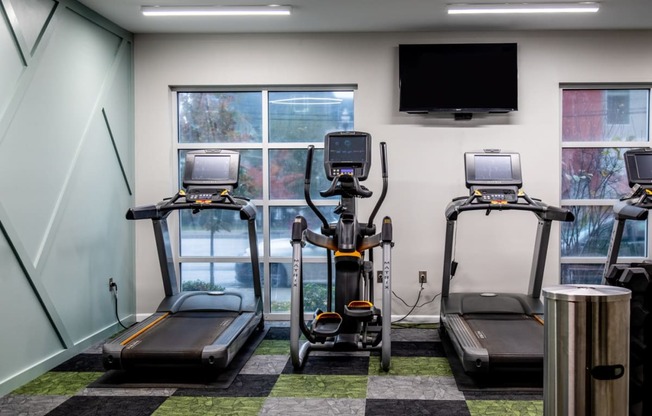 a gym with four treadmills and a tv on the wall at 310 at Nulu Apartments-Student, Louisville Kentucky