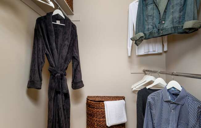 a closet with clothes hanging on the wall and a basket on the floor