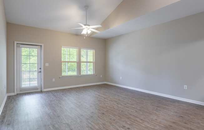 an empty living room with wood floors and a ceiling fan