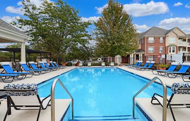 A large swimming pool surrounded by lounge chairs and trees.