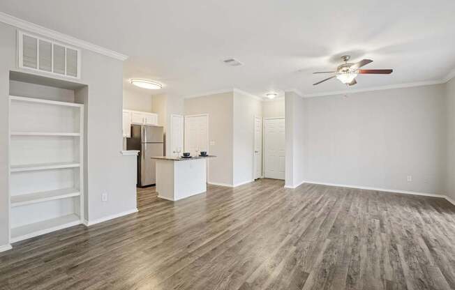 A spacious room with a ceiling fan and wooden flooring.