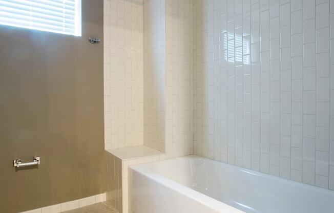 a bathroom with white tile and a white bathtub