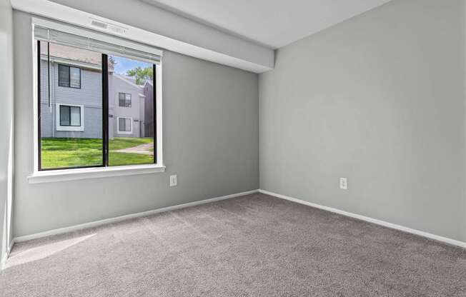 A room with a window showing a house across the street.