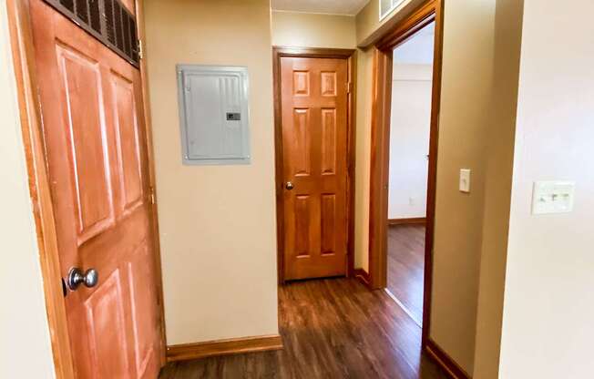 an empty hallway with a wooden door and a door to a bedroom and a hallway