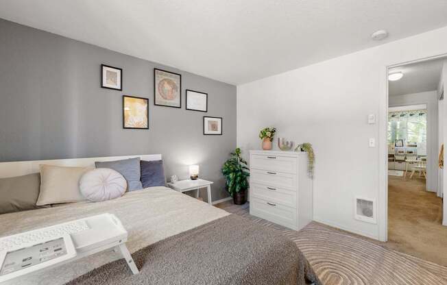 A bedroom with a bed, nightstand, and a wall with pictures at Clackamas Trails Apartments, Oregon, 97222