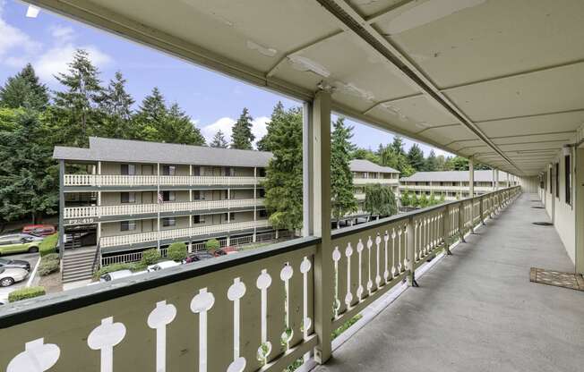 a balcony with a white fence and a large building in the background at Swiss Gables Apartment Homes, Kent, 98032