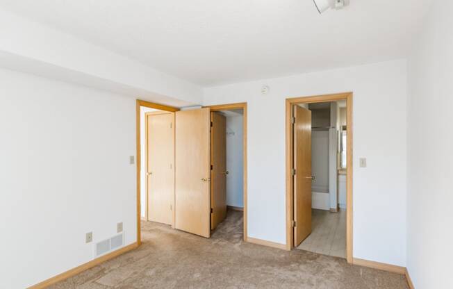 an empty room with three doors and a carpeted floor