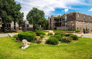 A stone lion statue sits in a green grassy area in front of a building.