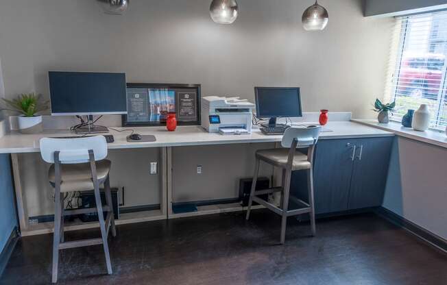 a computer desk with three stools and two monitors