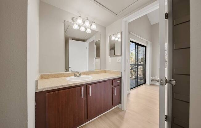 A bathroom with a sink, mirror, and wooden cabinets.