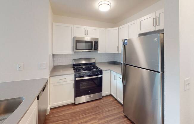 a two bedroom kitchen with stainless steel appliances and white cabinets