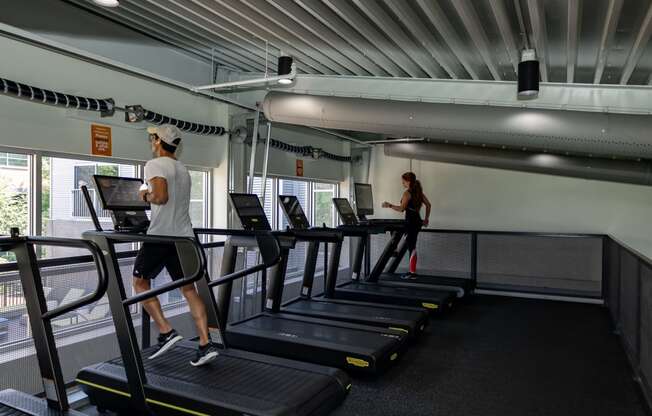 a man and a woman running on treadmills in a gym