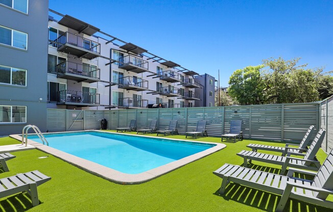 an image of an apartment complex with a swimming pool and lounge chairs