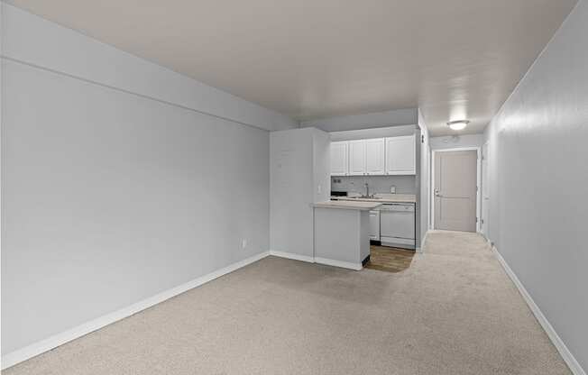 A white room with a kitchenette and a carpeted floor.