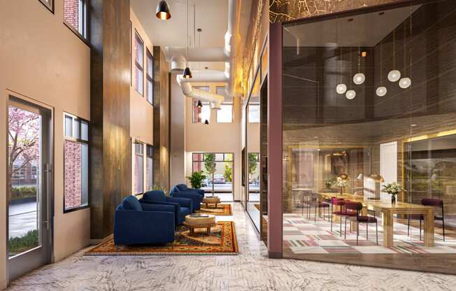 a lobby with blue couches and a table with chairs and a large glass door at Link Apartments® Broad Ave, Tennessee