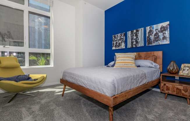 a bedroom with a blue accent wall and a bed with a wooden headboard