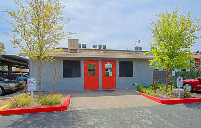 A building with a red door and a parking sign in front.