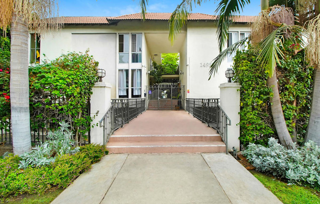 a house with palm trees and a sidewalk in front of it