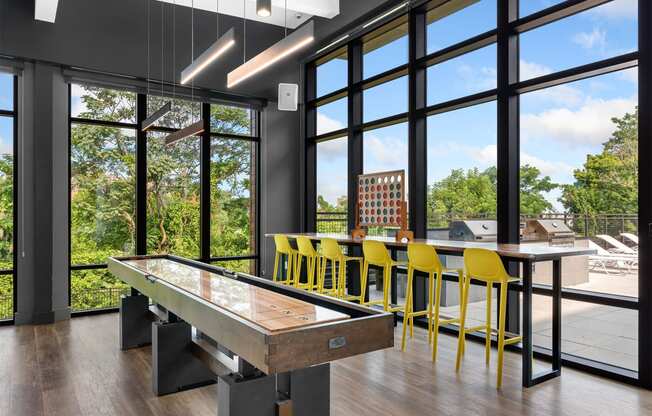 a games room with a shuffleboard table and yellow bar stools