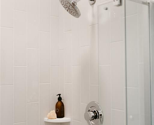 a white bathroom with a shower and a small shelf