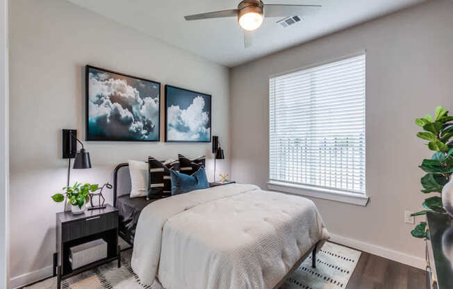 A bedroom with a bed, a chair, and a ceiling fan.