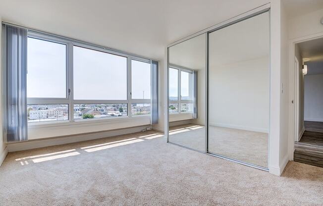 Merritt on 3rd Apartments in Oakland, CA, with wall-to-wall carpet, a huge closet, large windows, and white walls
