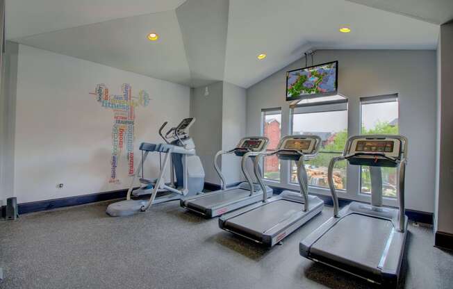 a workout room with treadmills and a tv