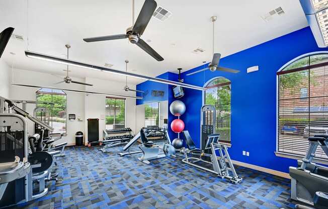 a gym with a blue wall and a ceiling fan