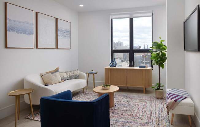 A living room with a white couch, a blue chair, a wooden cabinet, and a flat screen TV mounted on the wall.