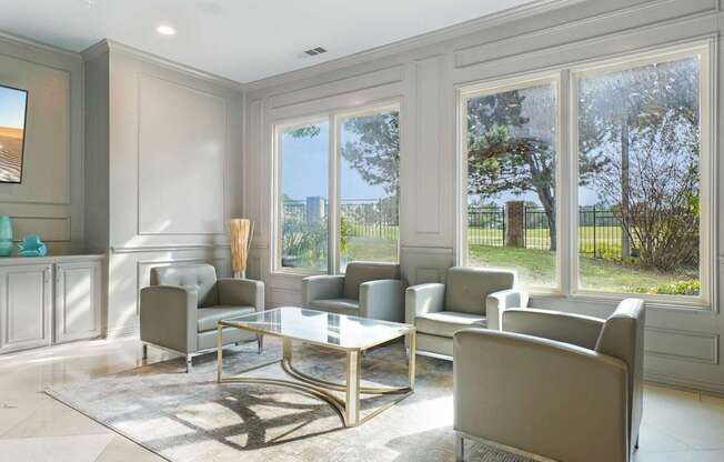 A living room with a glass table and grey chairs.